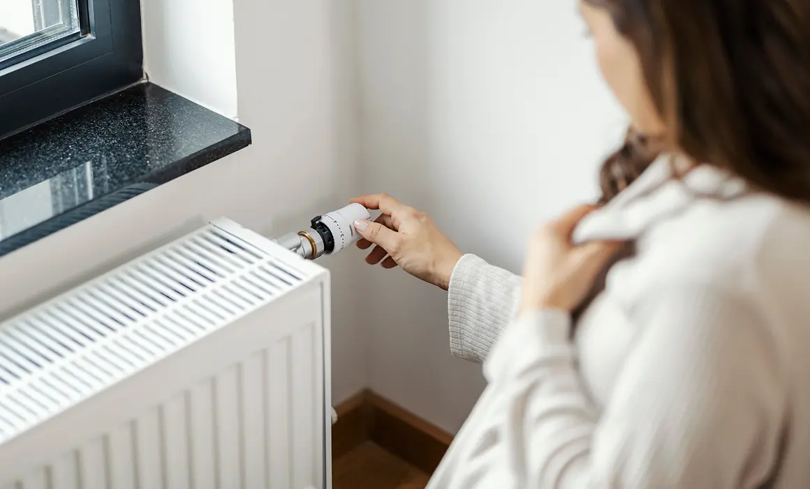 Une femme modifiant la températeur d'une vanne thermostatique